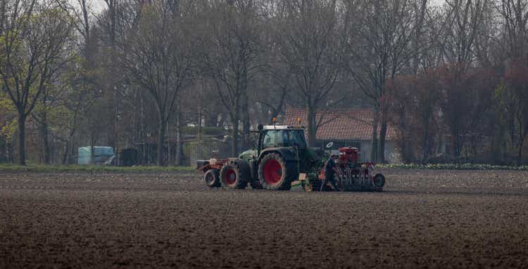 Beautiful shot of a man making maintenance on a Fendt tractor plowing in an agriculture field