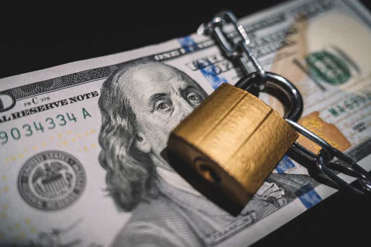 Heap of money in chain with padlock on black. Business safety or financial protection or restriction access. concept of keeping or banning cash dollars. money is banned.