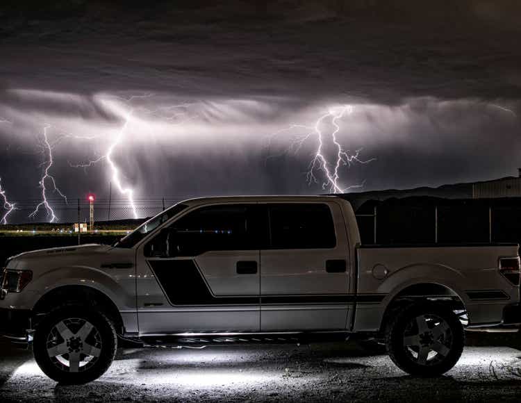 Side view of a Ford F150 parked on the street during a lightning shot in long exposure