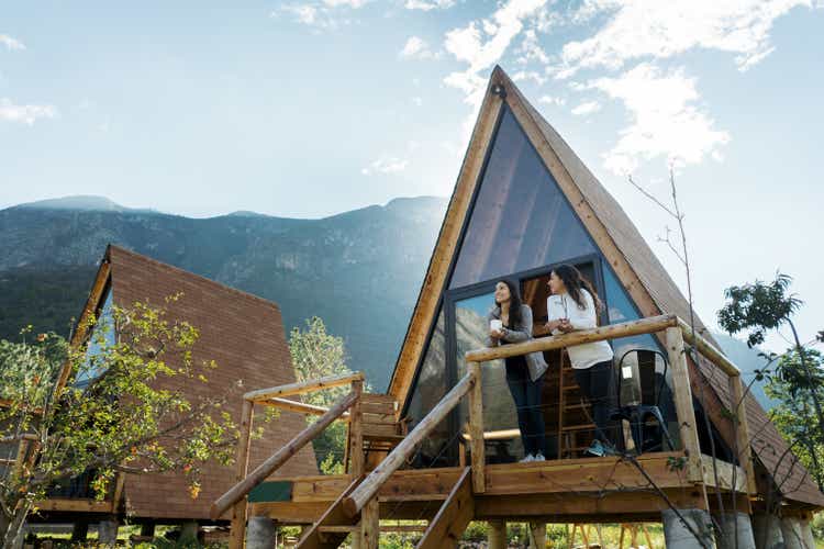 Two female friends enjoying hot drink outside of cabin