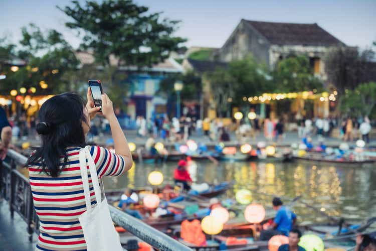 young woman taking picture of iluminated old town of Hoi An