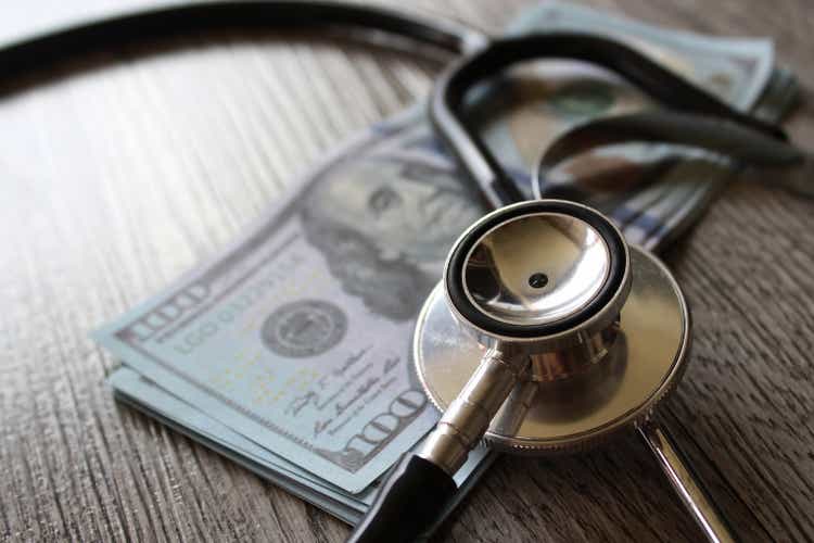 Stethoscope and money on wooden table