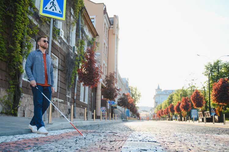 Blind young man crossing road