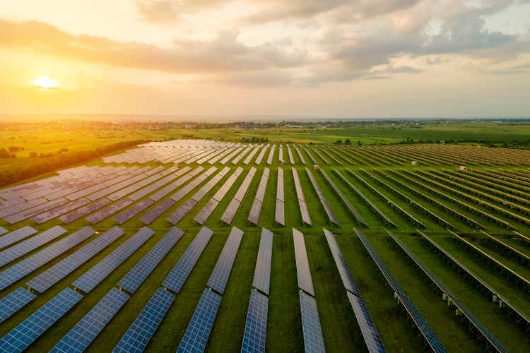 Aerial view of large electrical power plant with many rows of solar photovoltaic panels for producing clean ecological electric energy in morning. Renewable electricity with zero emission concept.