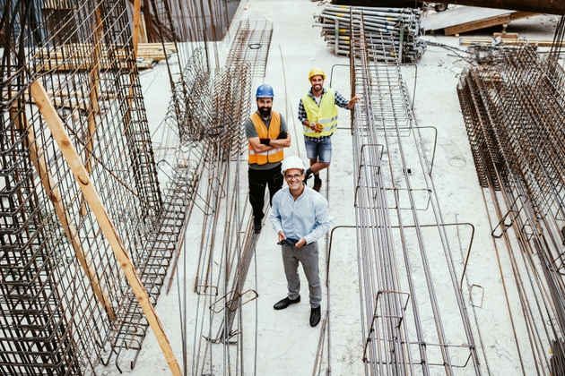Engineers on construction site, looking at camera and smiling. Employment in housing and real estate sector