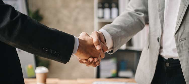 Two confident business man shaking hands during a meeting in the office, success, dealing, greeting and partner in sun light