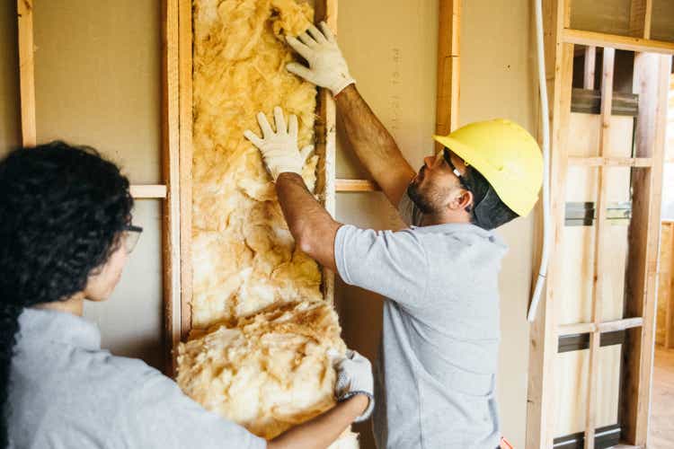 Construction workers install insulation