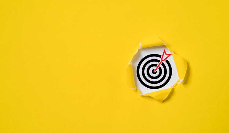 Dartboard with arrow inside of yellow punched paper for setup business objective target and goal concept.