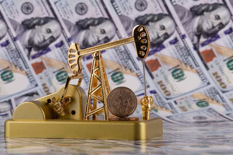 Eine goldene Miniatur-Ölpumpe und eine 1-Dollar-Münze gegen einen 100-Dollar-Schein