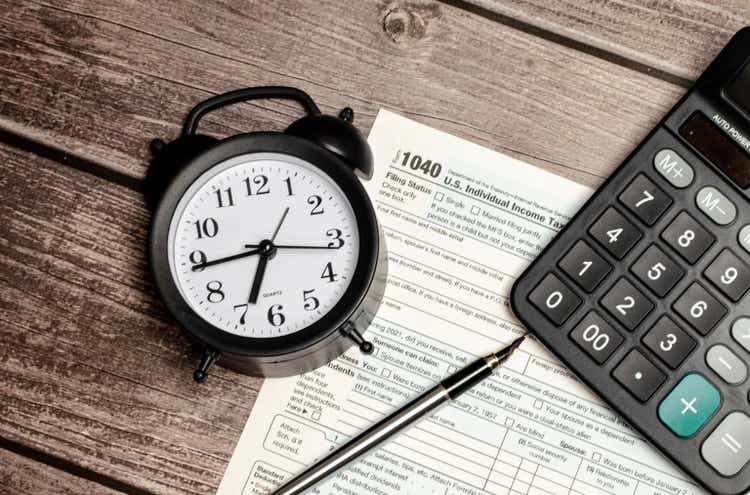 Top view tax form 1040 with pen, calculator and black alarm clock. tax time. financial document.