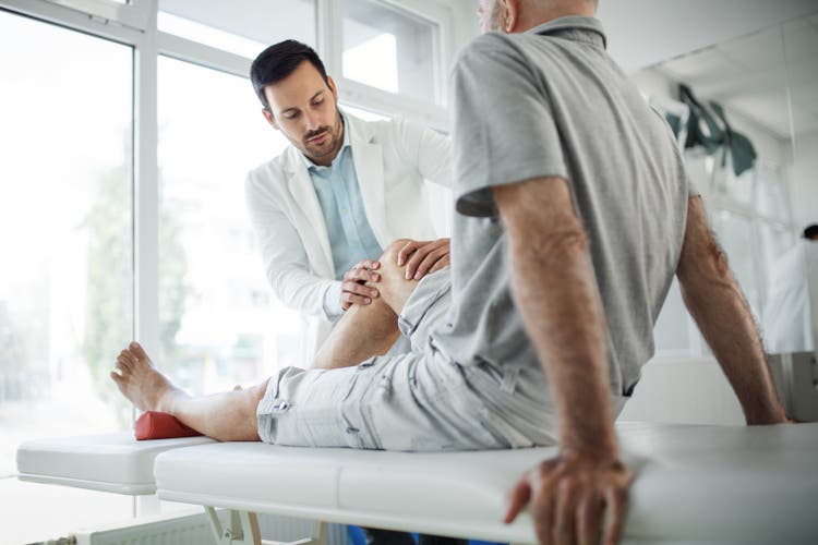 Senior man having his knee examined by a doctor.
