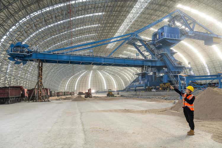 A female technician works at a large freight construction site