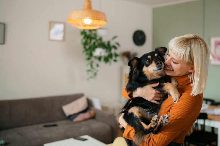 Fröhliche blonde Frau, die Zeit mit ihrem Hund zu Hause verbringt