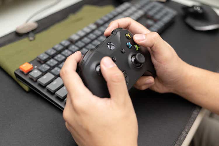 Hand holding Wireless gamepad for the Xbox One, a home video game console produced by Microsoft. Black Xbox game controller.