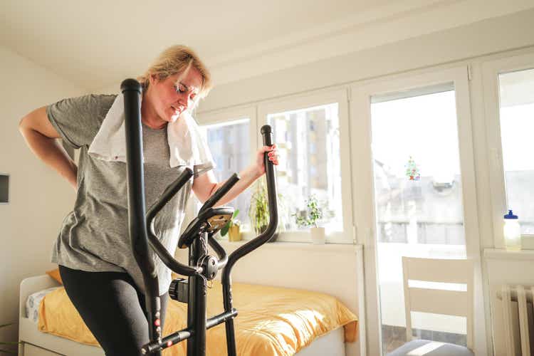 Caucasian woman with a backache, exercise on a Nordic ski exercise machine