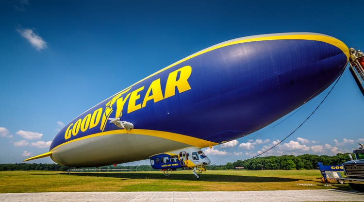 Closeup shot of a blue Goodyear blimp docked near the field