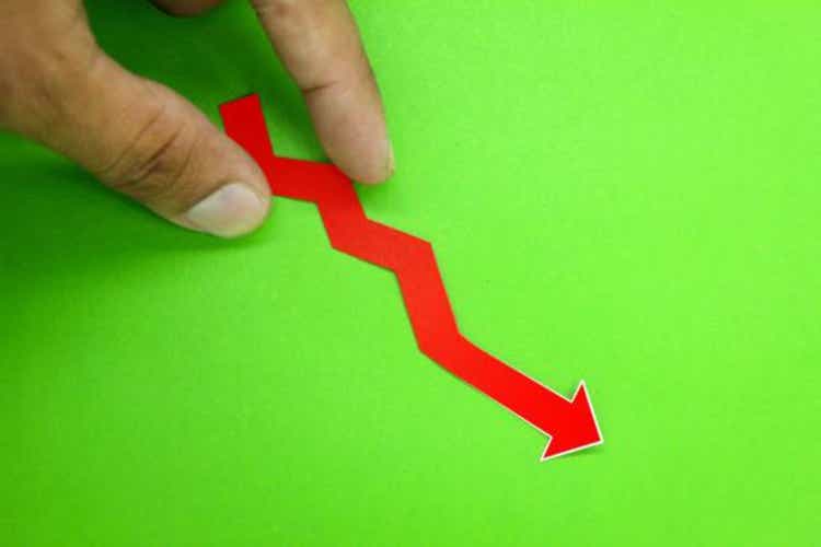 the hand holding the arrow of slump or fall. the economic concept is declining