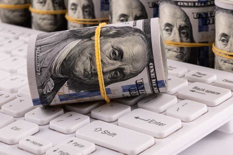 100 american dollar bills and computer keyboard
