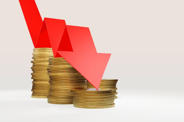 Red arrow jumping down stacks of golden coins. Illustration of the concept of recession, falling prices of currencies and financial crisis