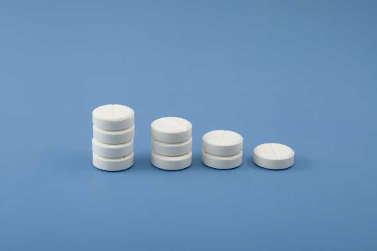 White placebo pills on blue background. Reducing medication intake and reducing dependence on antidepressants and sedative pills. Pharmaceutical histogram, Chart down. Design element