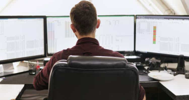 Young businessman working on multiple computer monitors at his desk