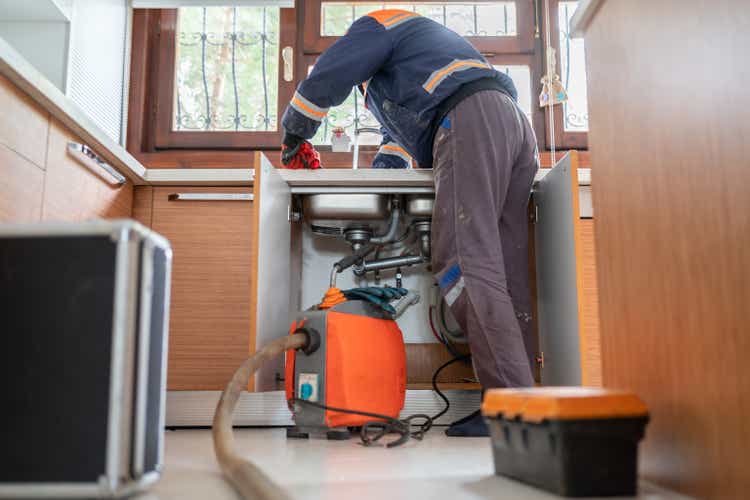 Plumber Unclogging A Kitchen Sink Drain