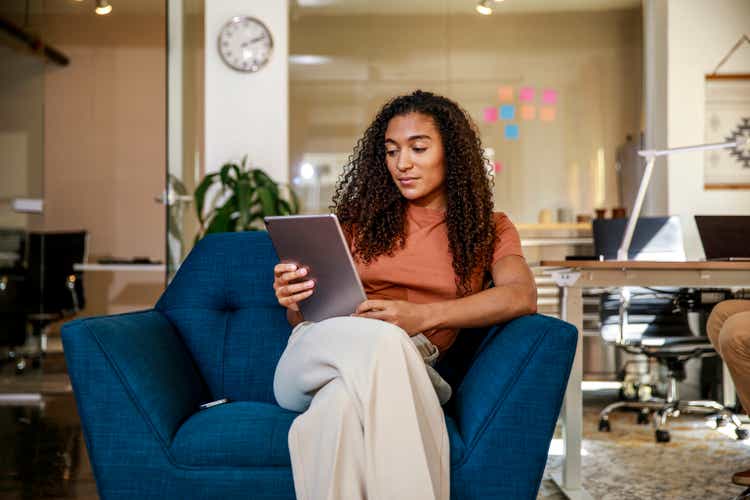 Young businesswoman tablet computer while sitting on armchair at office