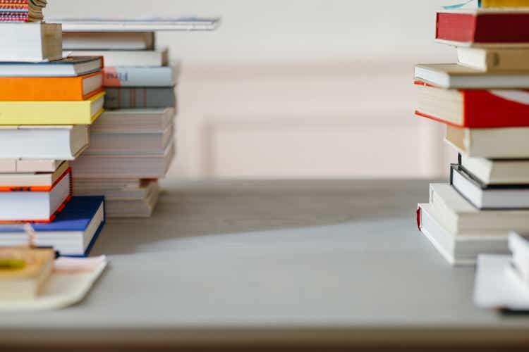 A View Of A Desk With Stacks Of Books On The Right And Left Side