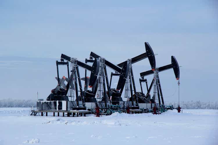 Winter in the oilfield cowered with white snow with black pumpjacks.