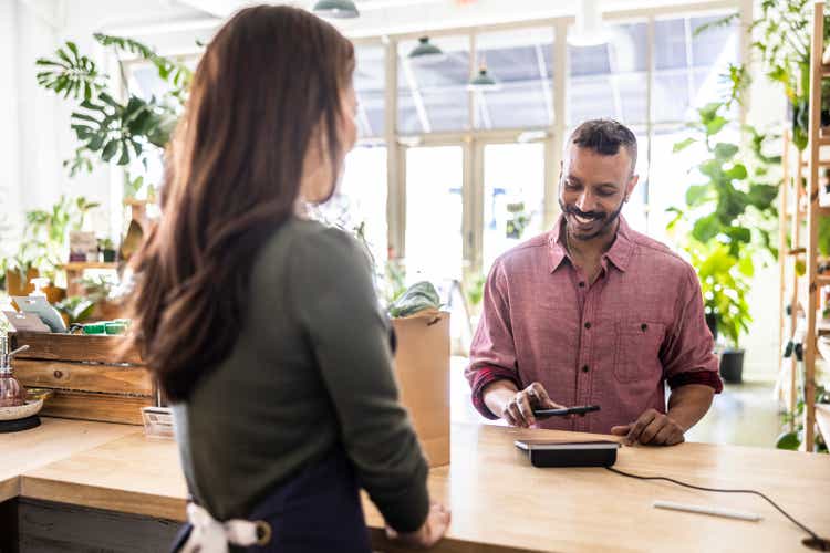 Man making a purchase at flower shop counter with credit card