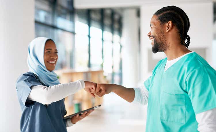 Teamwork, fist bump and tablet with nurses in hospital for medical, healthcare and support. Community, happy and friends with hands of people in clinic for medicine, collaboration and wellness