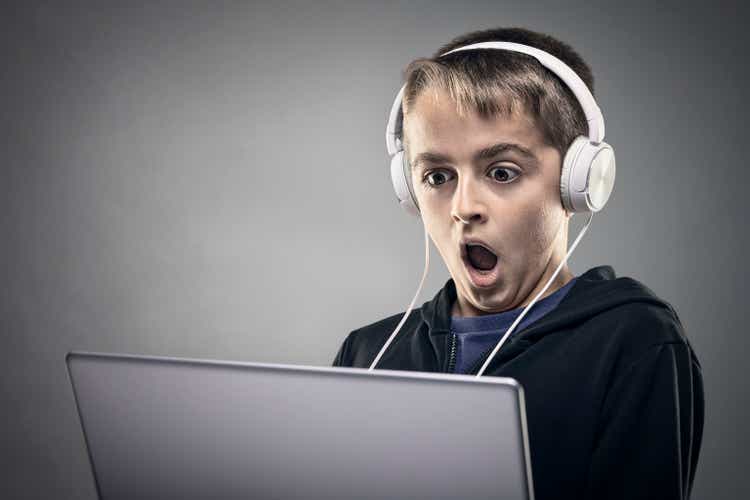 Shocked and surprised teenag boy on the internet with laptop computer