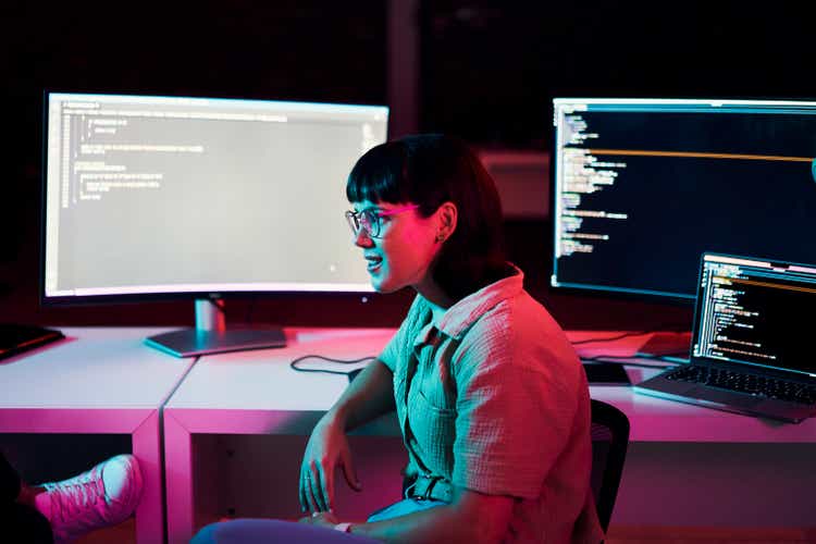 Computer coding, html scripting and female programming, software development or cyberpunk in neon.Information technology, code and programmer geek or person on data monitor screen at night or dark room