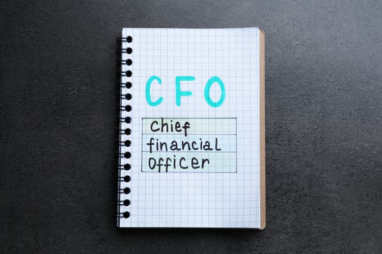 Notebook with abbreviation CFO (Chief Financial Officer) on grey stone background, top view