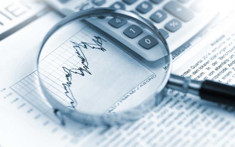 Magnifying glass, calculator and charts on paper