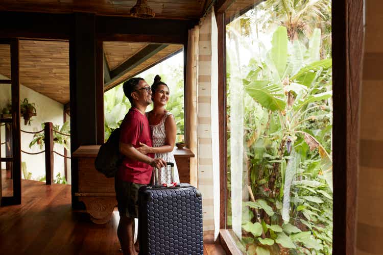 Happy couple standing near window at villa