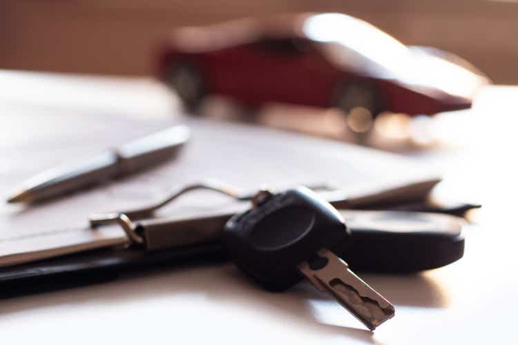 Car keys on purchase documents against the background of a red car