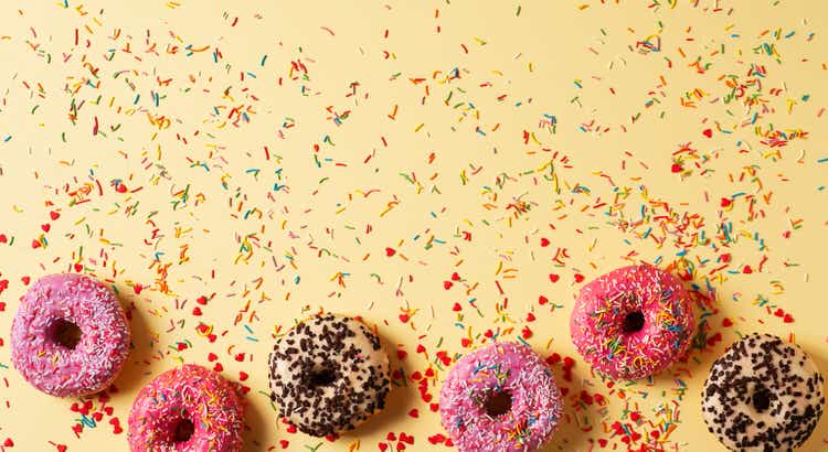 Colorful donuts with sprinkles on yellow background