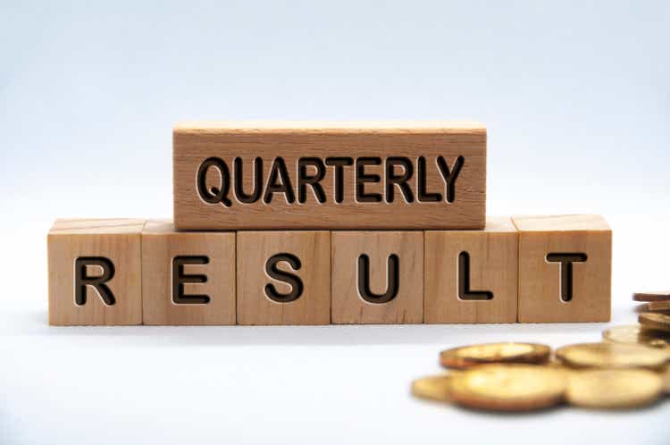 Quarterly result text engraved on wooden blocks with gold coins background.  Business achievement concept