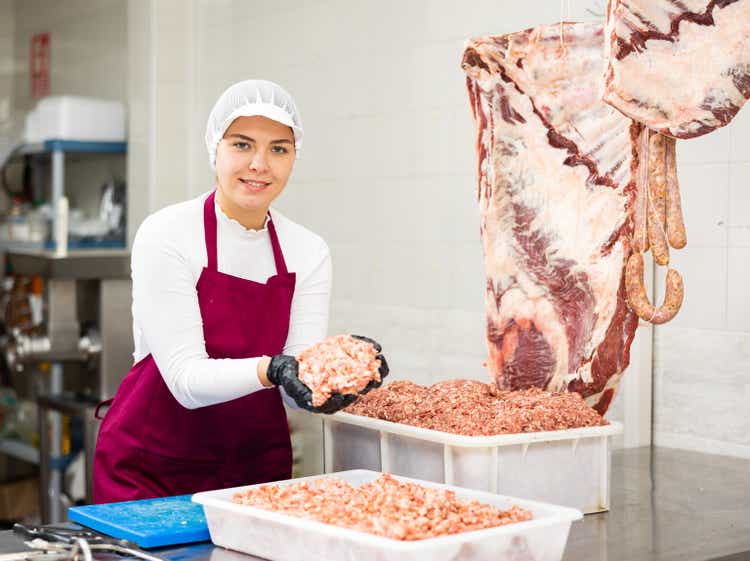 Young woman preparing minced meat in container