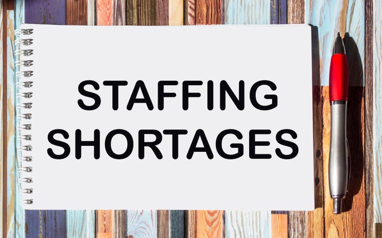 Business and finance concept. On a vintage background, a pen, a notepad with the inscription - Staffing Shortages