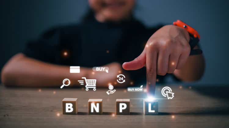 Women press their fingers on the wooden cubes with BNPL with online shopping icons. BNPL Buy now pays later online shopping concept.