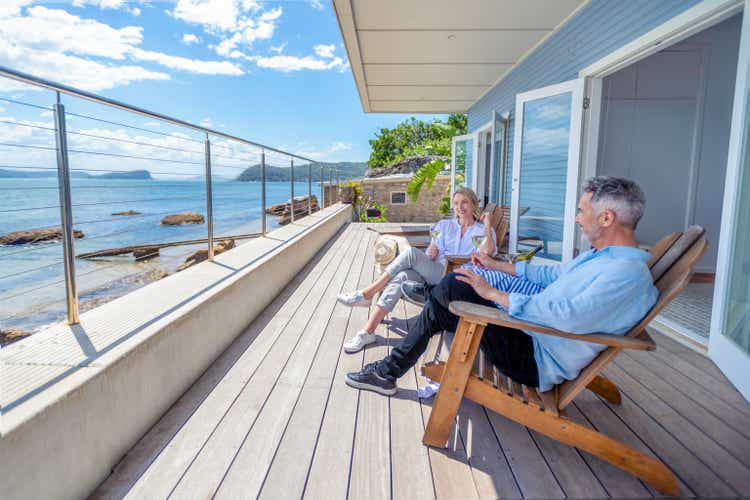 Mature couple drinking wine out on the deck in their waterfront home