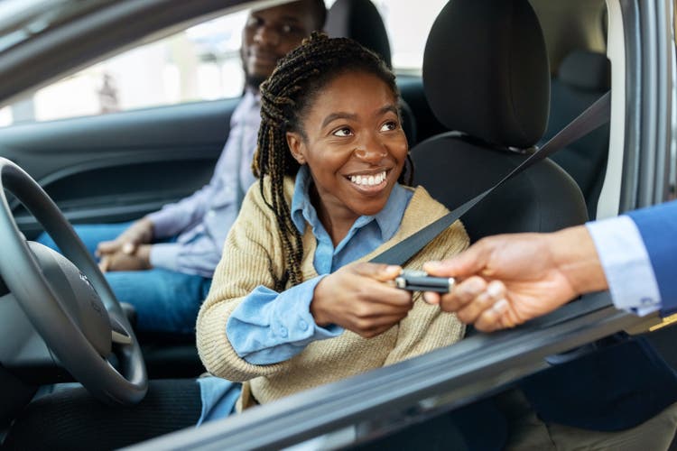 African couple getting car keys for test drive at showroom
