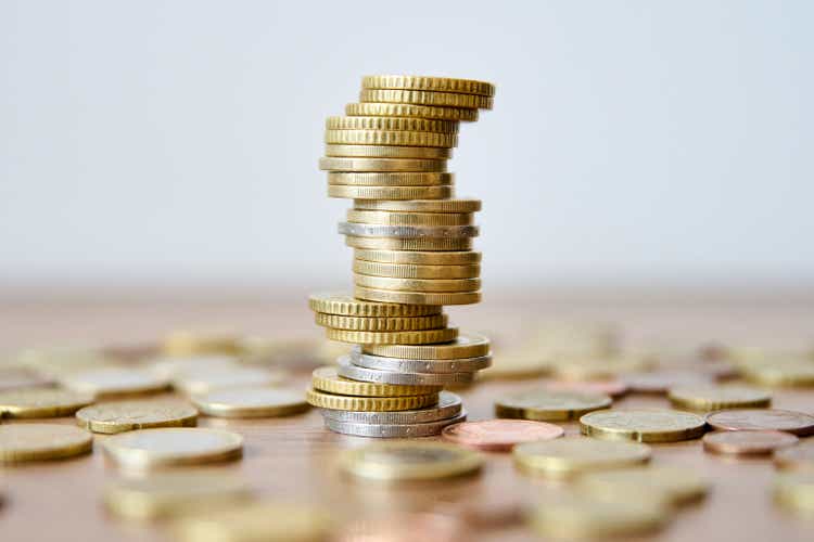 Pile of coins on wooden table with shallow depth of field