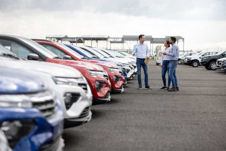 Salesman showing cars to a couple at the dealership