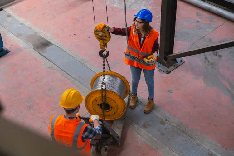 Young industry employees holding and working with remote control for operating crane