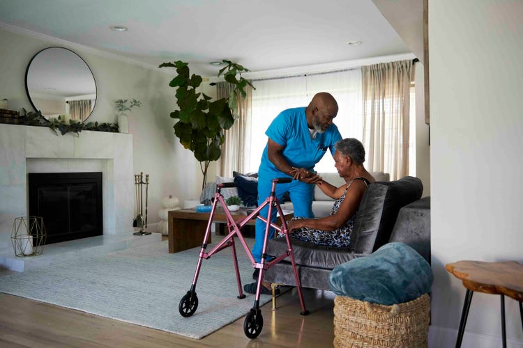 Male healthcare worker helping senior woman sit in chair