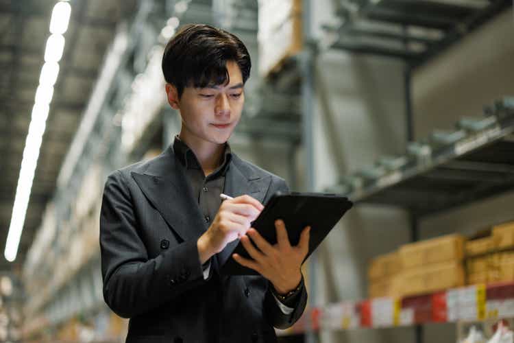 Young businessman in factory using digital tablet