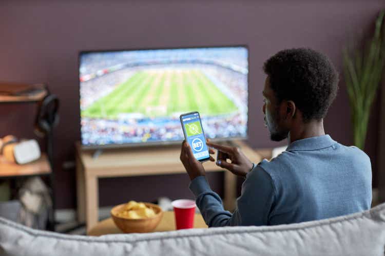 Man holding smartphone with sports bets app on screen